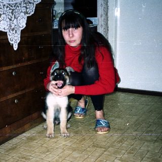 Woman crouches near a puppy in a tiled room.