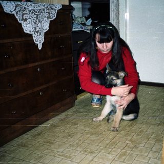Woman holds a puppy in a room with furniture.
