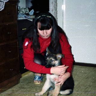 Woman holds a puppy in a room with furniture.