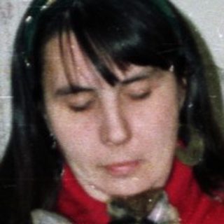Woman holds cat indoors near a Christmas tree.