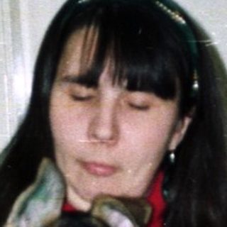 Woman holds German Shepherd puppy near a decorated Christmas tree.