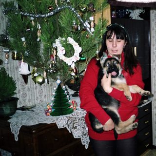 Woman holding a puppy near a Christmas tree.