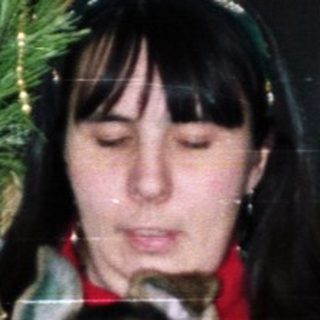 Woman holding a puppy near a Christmas tree.