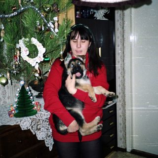 Woman holding a puppy near a Christmas tree.