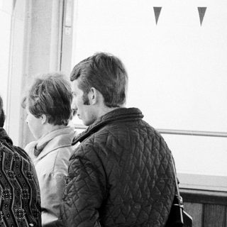Three people observe something through a window.