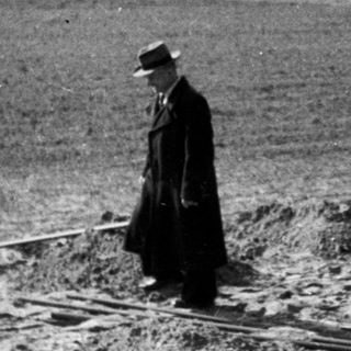 People observe a field, possibly after excavation or disturbance.