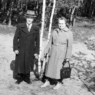Black and white photo of a couple standing near birch trees.