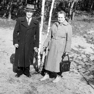 Black and white photo of a couple standing near birch trees.