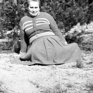 Woman kneeling in a field, with a person nearby.