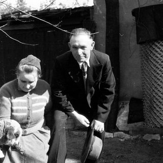 Man and woman with lamb in a rural setting.