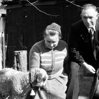 Man and woman with lamb in a rural setting.