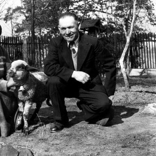 Couple poses with a young lamb in a yard.