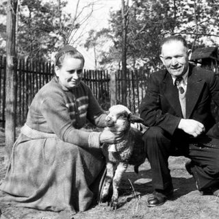 Couple poses with a lamb in a rural setting.