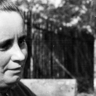 Woman holding a cat outdoors in a black and white photo.