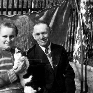 Black and white photo shows a couple holding a cat.