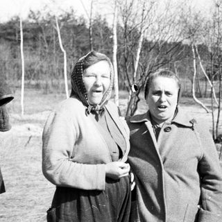 Two women standing outdoors in a rural setting.