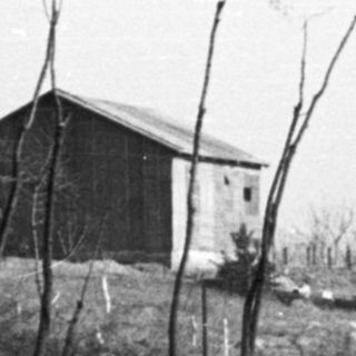 Man rests in excavated ground with buildings in background.
