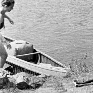 Here's a brief summary of the image: Boats on a shoreline, person visible near the water.