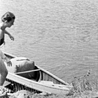 Here's a brief summary of the image: Boats on a shoreline, person visible near the water.