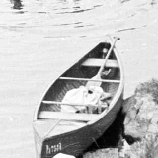 People swimming near canoes on a lake, vintage photo.