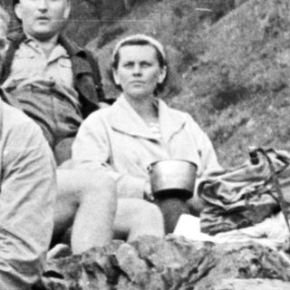 Group of people resting on a rocky hillside.