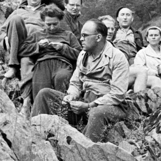 Group of people resting on a rocky hillside.