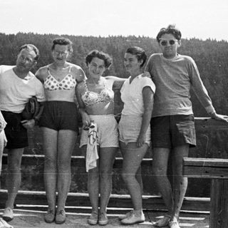 Group of people posing on a railing overlooking a forest.