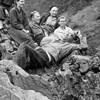 Group of people relaxing on a rocky hillside.