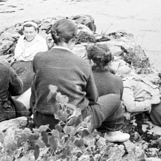 Group of people relaxing on rocks by water.