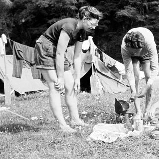 Three people camping and preparing food outdoors.