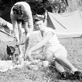 Three people camping and preparing food outdoors.
