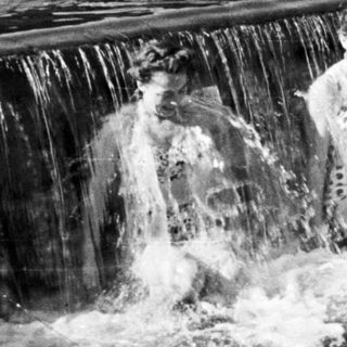 People enjoying a waterfall in a river setting.