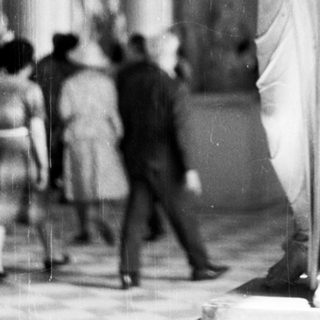 Marble statue displayed in a museum, people observing.