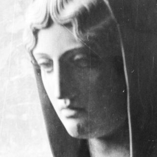 Here's a brief summary: Marble bust of a woman wearing a hood on a pedestal.