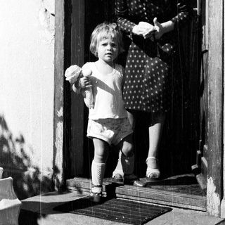 Child and woman stand on a doorstep.