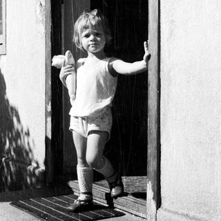 Here's a brief summary of the image: Child stands in a doorway, holding an object.