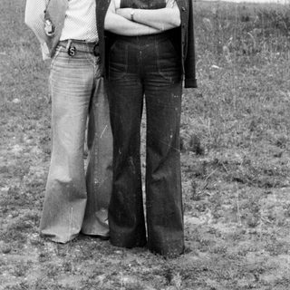 Couple posing outdoors, wearing 1970s style clothing.