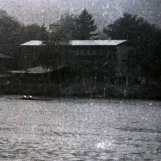 Water scene with a building and trees in the background.