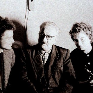 Here's a brief summary of the image: Three people are seated together in a formal setting.