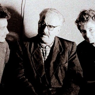 Here's a brief summary of the image: Three people are seated together in a formal setting.