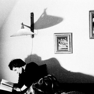 Person reading in a room, lit by a lamp.