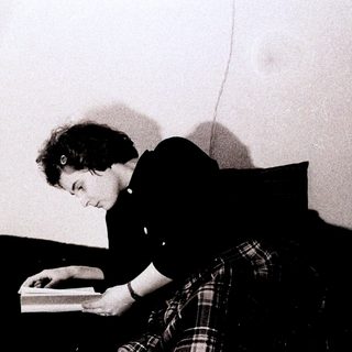 Person reading a book while seated on the floor.