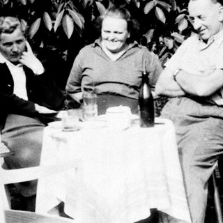 Three people seated at a table outdoors.