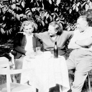 Three people seated at a table outdoors.