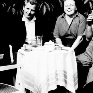Three people seated at a table, enjoying drinks outdoors.