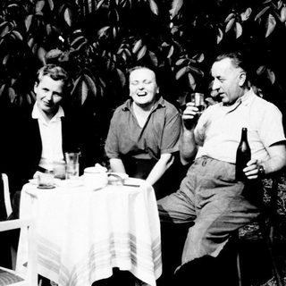 Three people seated at a table, enjoying drinks outdoors.