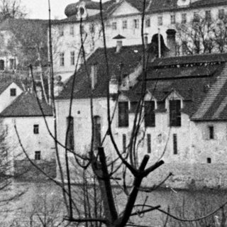 Black and white photo shows a town alongside a river.