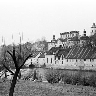Black and white photo of a castle beside a river.
