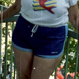 Woman stands on a balcony wearing athletic clothes.