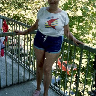 Woman stands on a balcony wearing athletic clothes.